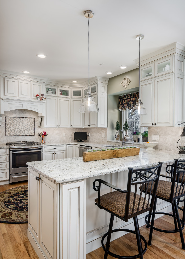 Large elegant u-shaped medium tone wood floor and brown floor eat-in kitchen photo in Philadelphia with an undermount sink, raised-panel cabinets, white cabinets, quartz countertops, white backsplash, a peninsula and multicolored countertops