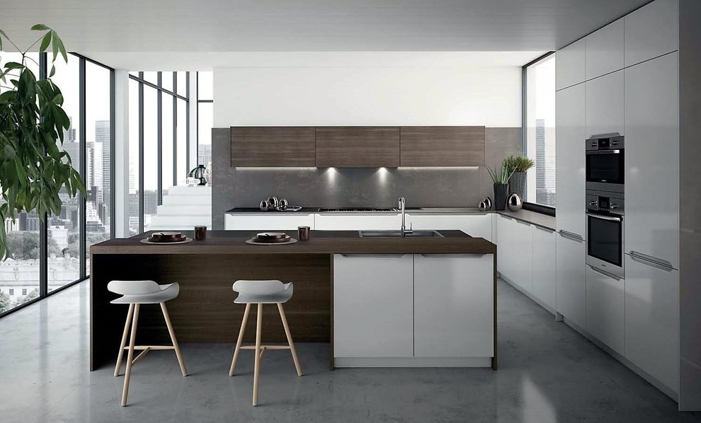 Example of a mid-sized minimalist l-shaped concrete floor and gray floor open concept kitchen design in New York with an undermount sink, flat-panel cabinets, white cabinets, wood countertops, gray backsplash, stone slab backsplash, stainless steel appliances and an island