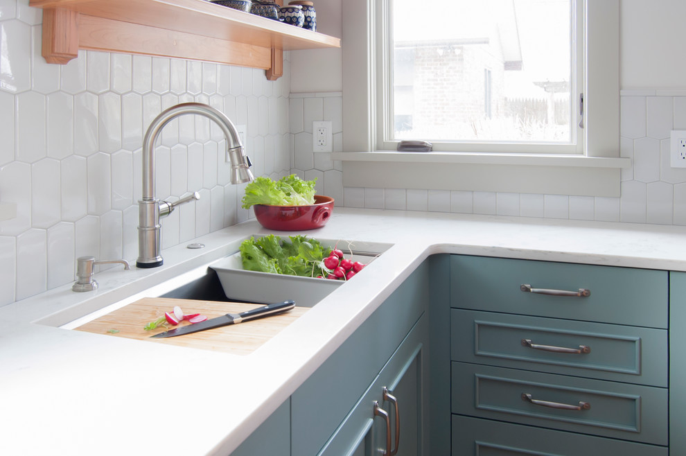 Photo of a medium sized farmhouse l-shaped enclosed kitchen in Chicago with a submerged sink, recessed-panel cabinets, green cabinets, engineered stone countertops, grey splashback, porcelain splashback, stainless steel appliances, cork flooring, a breakfast bar and brown floors.