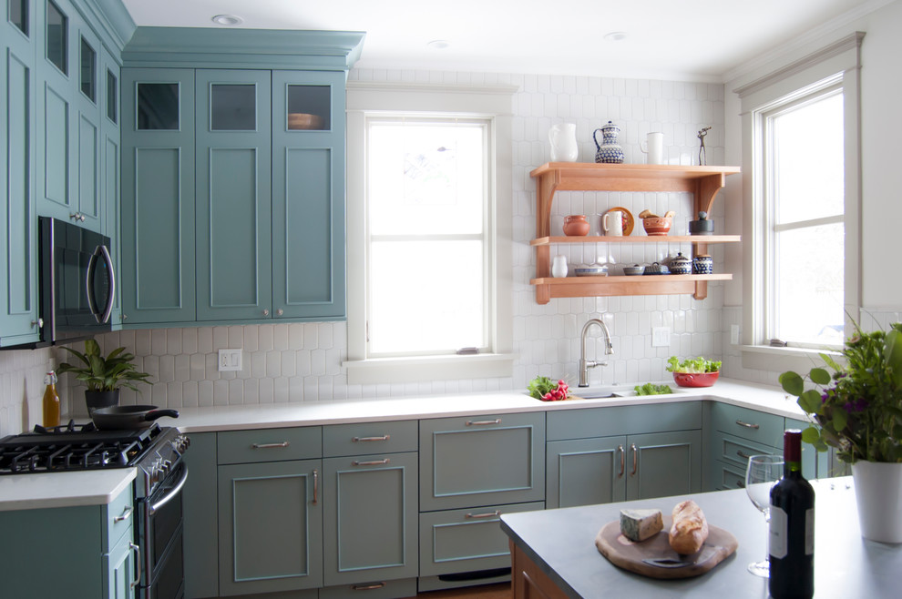 Foto på ett mellanstort lantligt l-kök, med en undermonterad diskho, luckor med infälld panel, gröna skåp, bänkskiva i kvarts, grått stänkskydd, stänkskydd i porslinskakel, rostfria vitvaror, korkgolv, en halv köksö och brunt golv