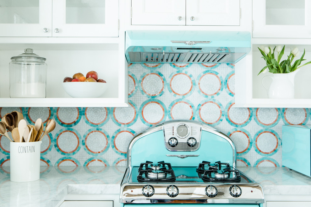 Foto på ett litet maritimt kök, med en undermonterad diskho, luckor med profilerade fronter, vita skåp, bänkskiva i kvarts, flerfärgad stänkskydd, stänkskydd i mosaik, färgglada vitvaror, mellanmörkt trägolv och en köksö