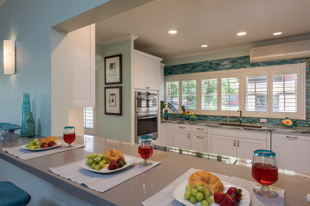 Enclosed kitchen - mid-sized tropical vinyl floor and gray floor enclosed kitchen idea in Hawaii with an undermount sink, shaker cabinets, white cabinets, quartzite countertops, blue backsplash, glass tile backsplash, paneled appliances and no island