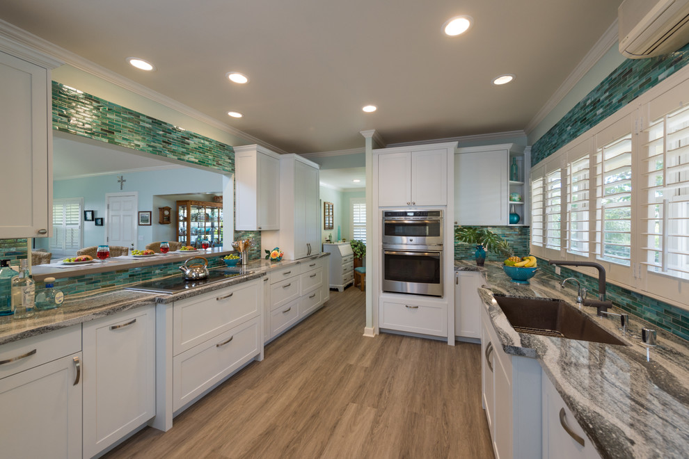 ハワイにある中くらいなトロピカルスタイルのおしゃれな独立型キッチン (アンダーカウンターシンク、シェーカースタイル扉のキャビネット、白いキャビネット、珪岩カウンター、青いキッチンパネル、ガラスタイルのキッチンパネル、パネルと同色の調理設備、クッションフロア、アイランドなし、グレーの床) の写真