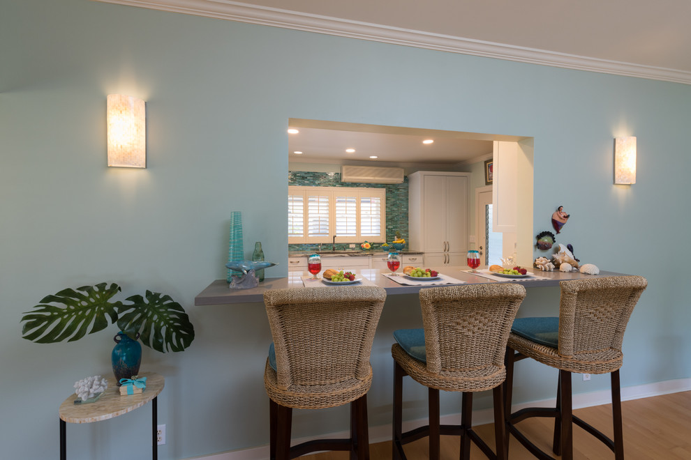 ハワイにある中くらいなトロピカルスタイルのおしゃれな独立型キッチン (アンダーカウンターシンク、シェーカースタイル扉のキャビネット、白いキャビネット、珪岩カウンター、青いキッチンパネル、ガラスタイルのキッチンパネル、パネルと同色の調理設備、クッションフロア、アイランドなし、グレーの床) の写真