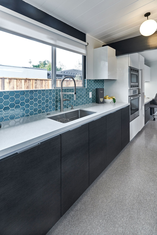 Modern inredning av ett stort linjärt kök och matrum, med en enkel diskho, släta luckor, grå skåp, bänkskiva i kvarts, blått stänkskydd, stänkskydd i keramik, rostfria vitvaror, linoleumgolv, en köksö och grått golv