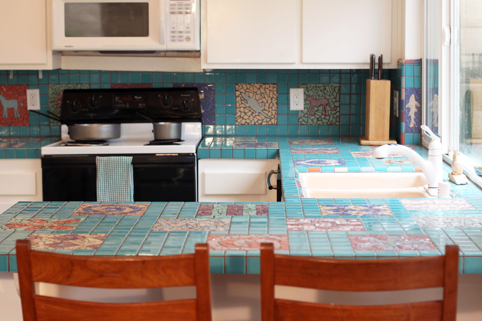 На фото: п-образная кухня в стиле фьюжн с плоскими фасадами, белыми фасадами, столешницей из плитки, разноцветным фартуком, фартуком из керамической плитки и черной техникой