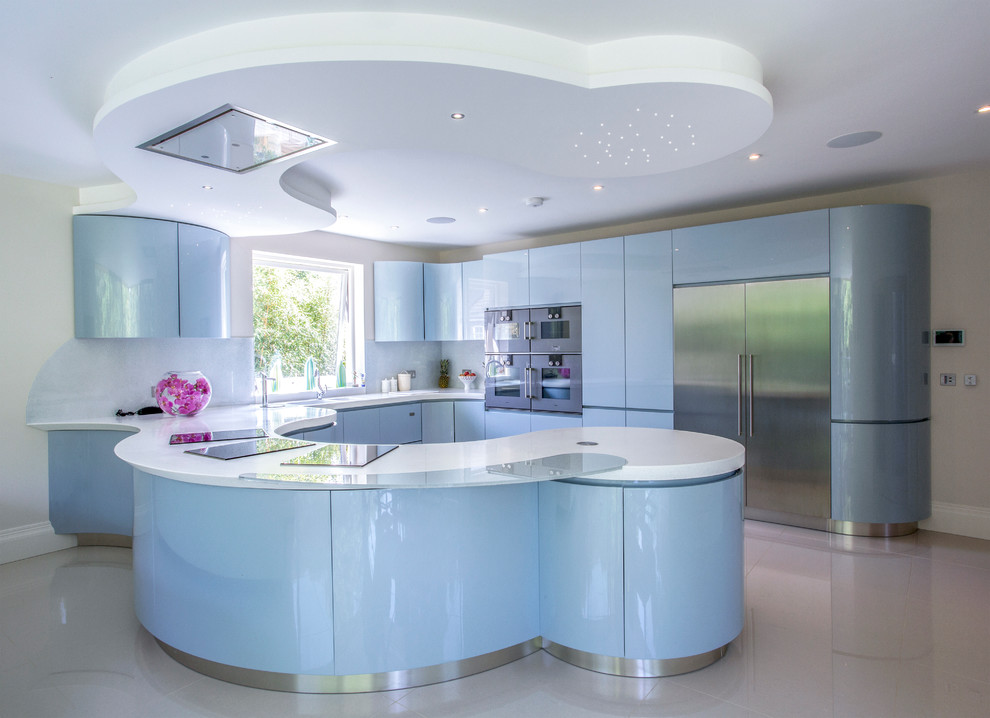 This is an example of an expansive modern l-shaped open plan kitchen in London with an integrated sink, flat-panel cabinets, blue cabinets, composite countertops, grey splashback, glass sheet splashback, stainless steel appliances, porcelain flooring and a breakfast bar.