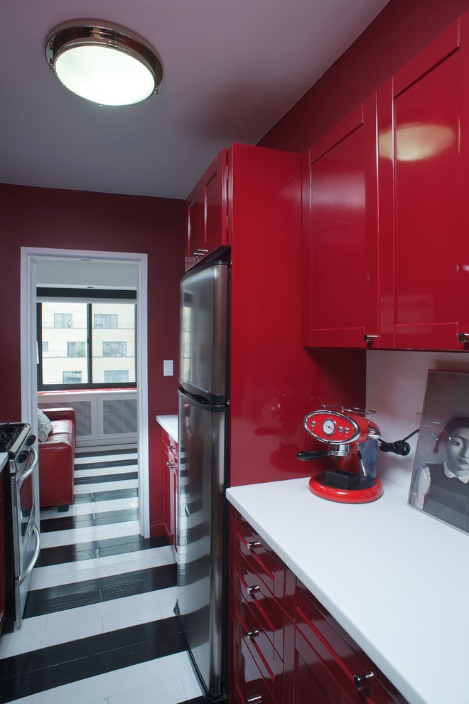 Idée de décoration pour une cuisine design avec un placard à porte shaker, des portes de placard rouges, un plan de travail en quartz et un électroménager en acier inoxydable.