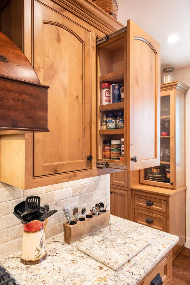 Example of a large tuscan l-shaped dark wood floor and brown floor eat-in kitchen design in San Luis Obispo with a drop-in sink, recessed-panel cabinets, medium tone wood cabinets, quartz countertops, beige backsplash, stone tile backsplash, stainless steel appliances, an island and beige countertops
