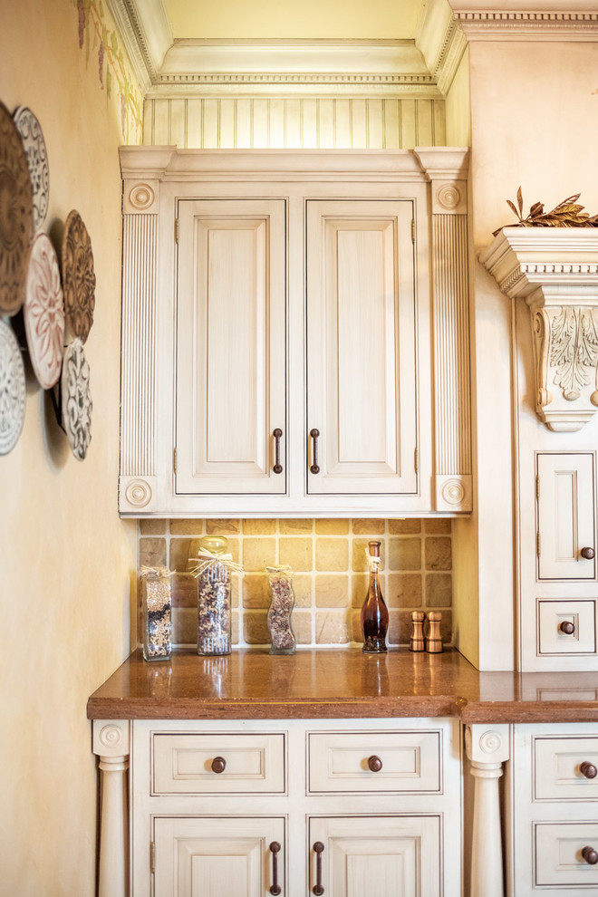 Cette photo montre une cuisine méditerranéenne avec un placard avec porte à panneau encastré, des portes de placard beiges, un plan de travail marron et un plan de travail en surface solide.