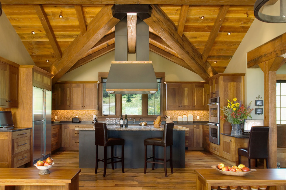 На фото: п-образная кухня в стиле рустика с фасадами в стиле шейкер, фасадами цвета дерева среднего тона и техникой из нержавеющей стали