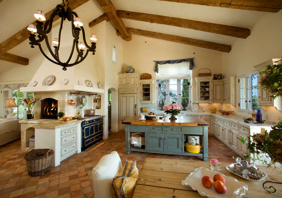 Foto di una cucina mediterranea con ante beige, paraspruzzi beige, elettrodomestici neri e ante con bugna sagomata