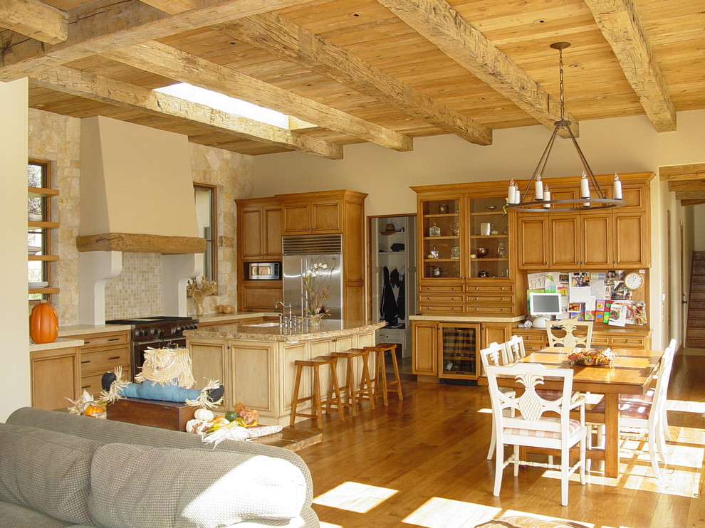 Medelhavsstil inredning av ett kök, med luckor med upphöjd panel, skåp i mellenmörkt trä, granitbänkskiva, stänkskydd i stenkakel och en köksö