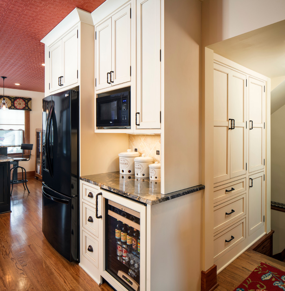 Exempel på ett mellanstort lantligt kök, med luckor med profilerade fronter, granitbänkskiva, beige stänkskydd, stänkskydd i stenkakel, svarta vitvaror, mellanmörkt trägolv, en köksö, en rustik diskho och beige skåp