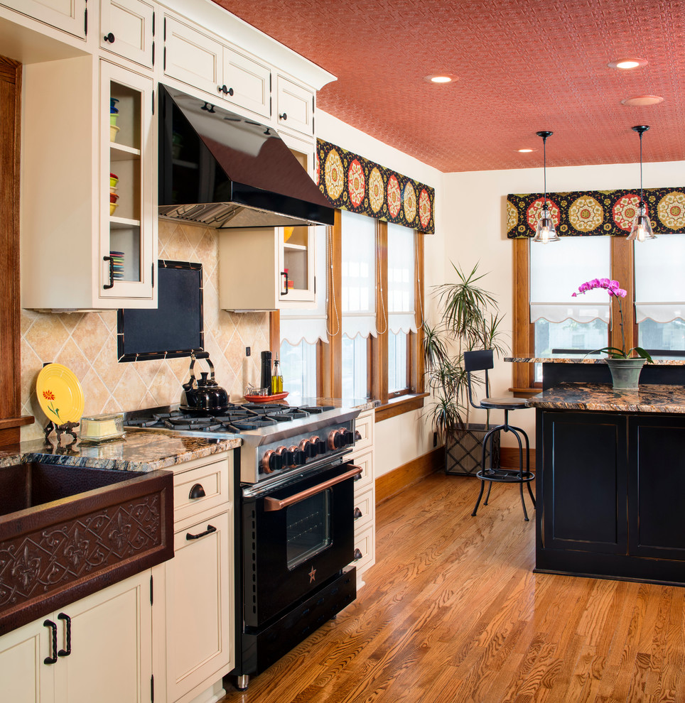 Inspiration for a mid-sized timeless galley medium tone wood floor eat-in kitchen remodel in Omaha with a farmhouse sink, beaded inset cabinets, black cabinets, granite countertops, beige backsplash, stone tile backsplash, black appliances and an island