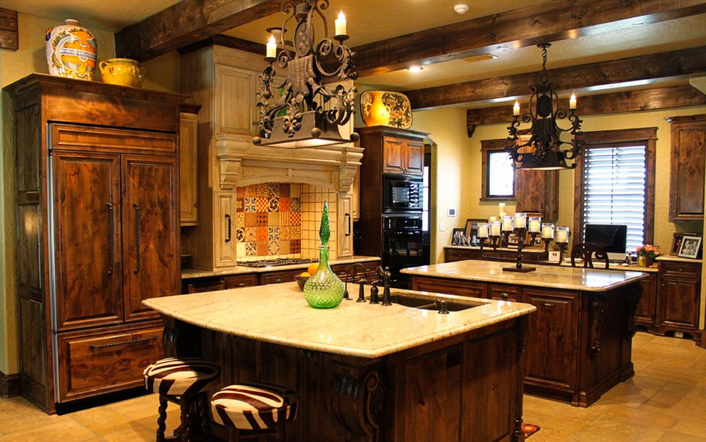 Example of a large tuscan l-shaped concrete floor eat-in kitchen design in Dallas with an undermount sink, raised-panel cabinets, distressed cabinets, multicolored backsplash, black appliances and two islands