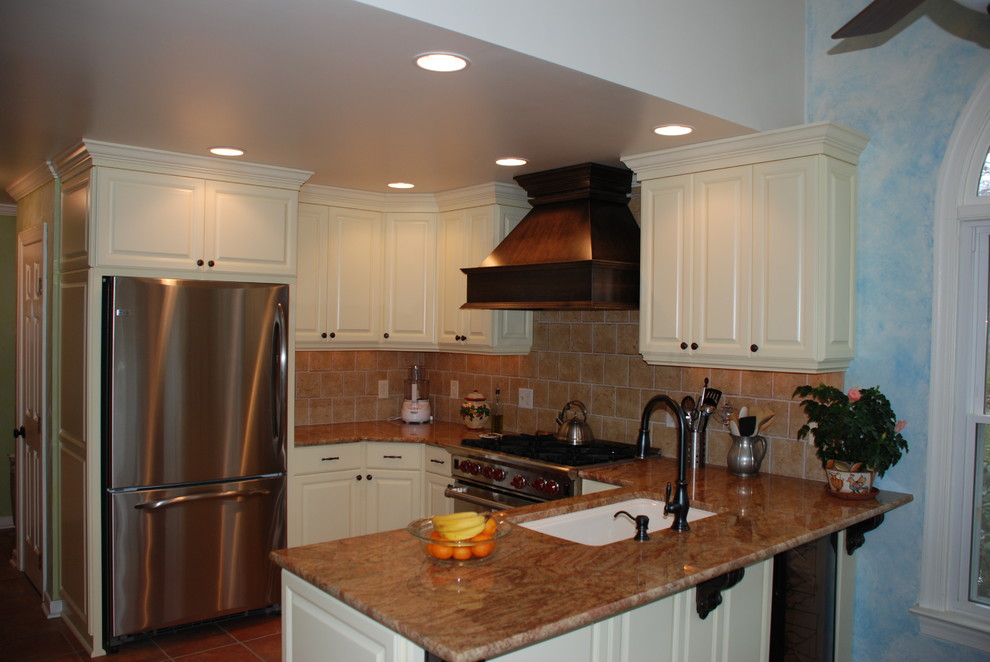 Inspiration for a timeless u-shaped eat-in kitchen remodel in Richmond with an undermount sink, raised-panel cabinets, yellow cabinets, granite countertops, brown backsplash, ceramic backsplash and stainless steel appliances