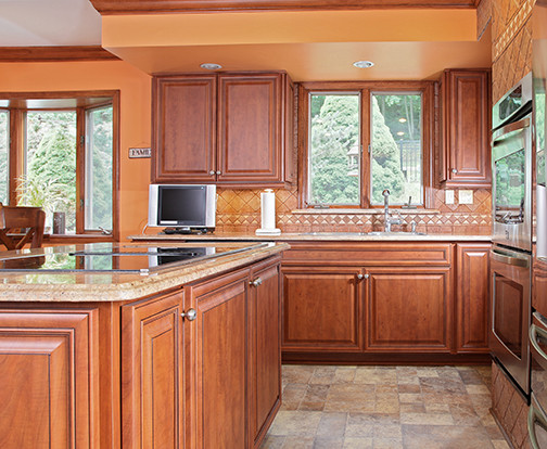 Mid-sized tuscan l-shaped porcelain tile and brown floor kitchen photo in Other with a single-bowl sink, raised-panel cabinets, granite countertops, brown backsplash, stone tile backsplash and stainless steel appliances
