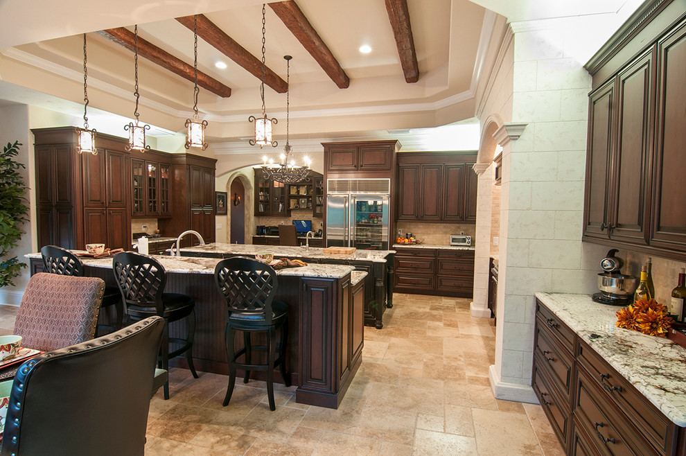 Inspiration for a large mediterranean u-shaped ceramic tile and beige floor open concept kitchen remodel in Orlando with an undermount sink, raised-panel cabinets, dark wood cabinets, granite countertops, beige backsplash, cement tile backsplash, stainless steel appliances, an island and beige countertops