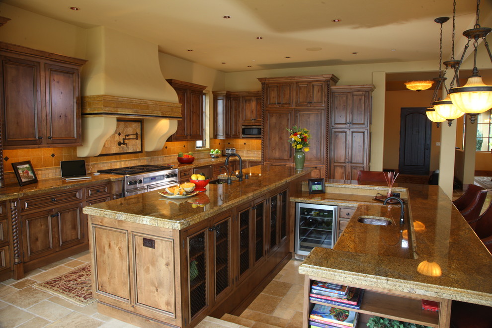 Klassisk inredning av ett stort kök, med en undermonterad diskho, luckor med infälld panel, skåp i mellenmörkt trä, granitbänkskiva, gult stänkskydd, stänkskydd i keramik, rostfria vitvaror, klinkergolv i porslin och flera köksöar