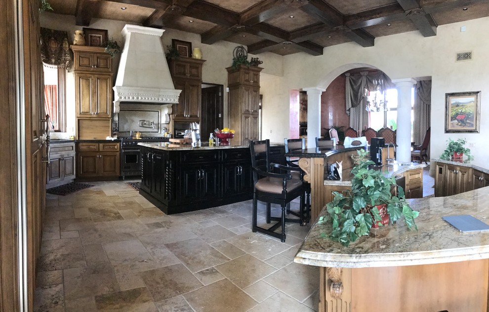 Rustikale Küche mit Unterbauwaschbecken, profilierten Schrankfronten, braunen Schränken, Granit-Arbeitsplatte, Elektrogeräten mit Frontblende, Kalkstein und zwei Kücheninseln in Phoenix