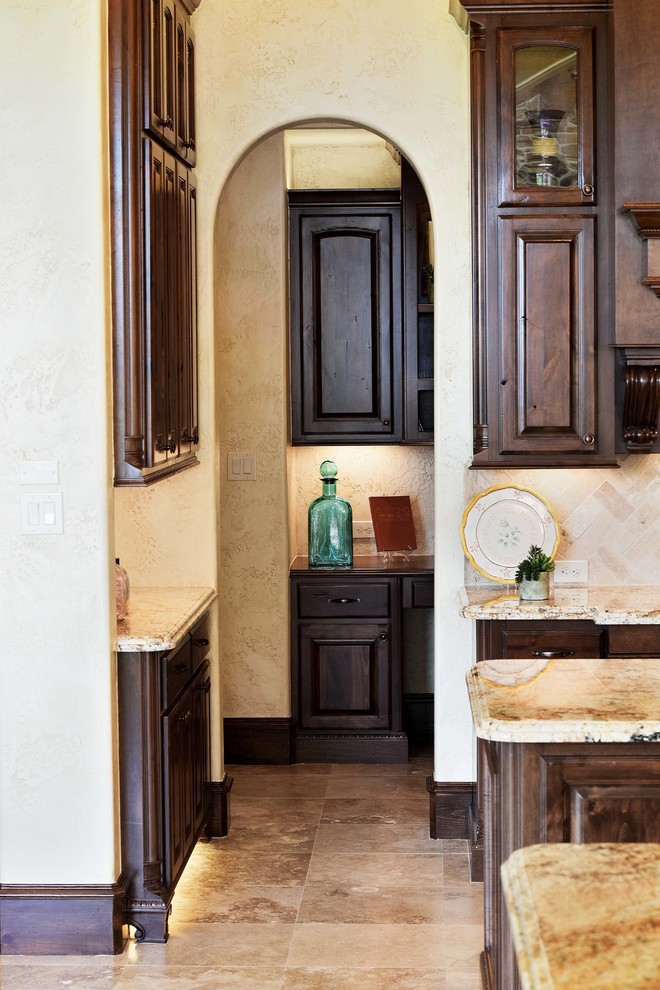 Immagine di una grande cucina mediterranea con ante con bugna sagomata, ante in legno bruno, top in granito, paraspruzzi beige, paraspruzzi con piastrelle in ceramica, pavimento in travertino e pavimento beige