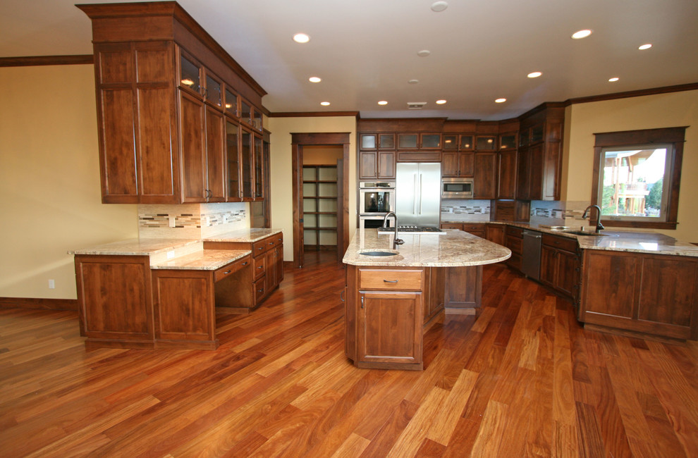 Exempel på ett stort medelhavsstil kök, med en undermonterad diskho, luckor med upphöjd panel, skåp i mellenmörkt trä, granitbänkskiva, beige stänkskydd, stänkskydd i stenkakel, rostfria vitvaror, mellanmörkt trägolv och en köksö