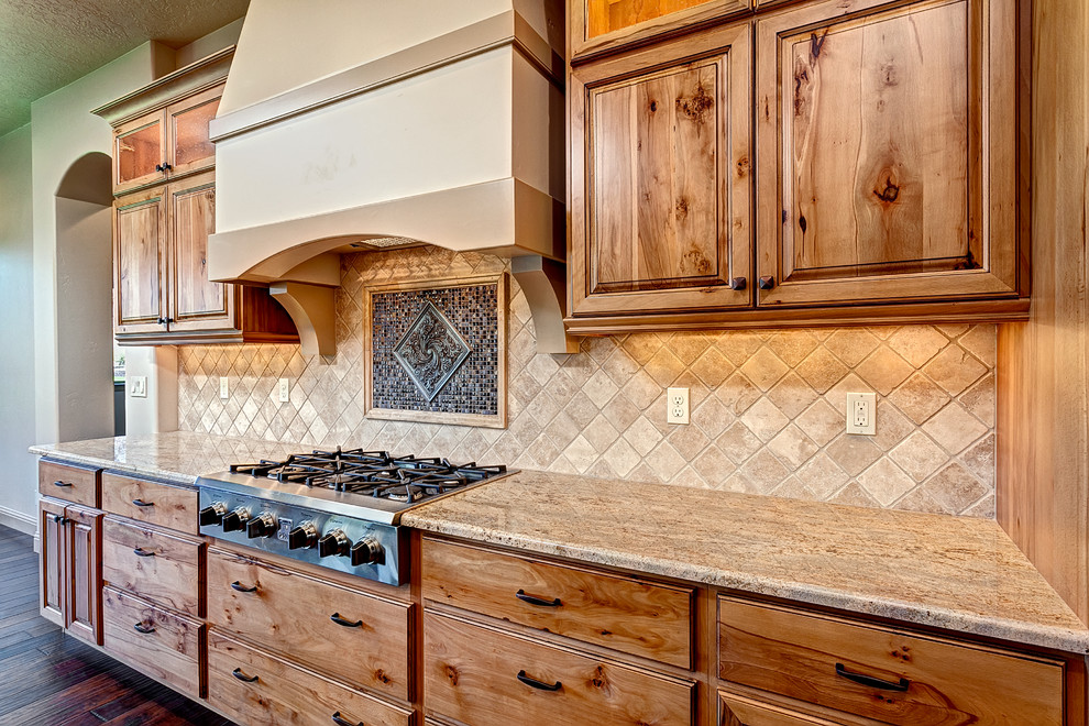 Foto på ett stort medelhavsstil kök, med luckor med upphöjd panel, skåp i mellenmörkt trä, granitbänkskiva, beige stänkskydd, stänkskydd i porslinskakel, rostfria vitvaror, mörkt trägolv och en köksö