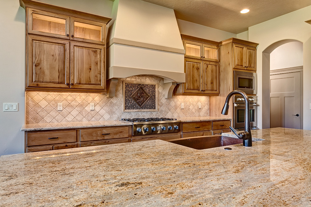 Large tuscan l-shaped dark wood floor open concept kitchen photo in Boise with raised-panel cabinets, medium tone wood cabinets, granite countertops, beige backsplash, porcelain backsplash, stainless steel appliances and an island