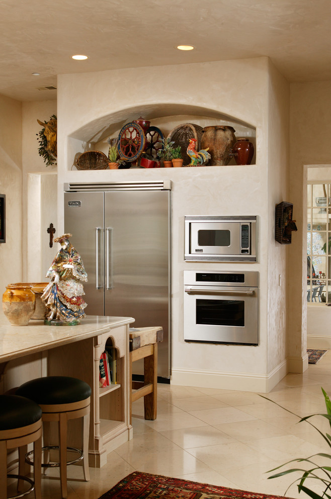 Exempel på ett stort medelhavsstil kök, med en rustik diskho, luckor med profilerade fronter, skåp i ljust trä, granitbänkskiva, beige stänkskydd, stänkskydd i stenkakel, rostfria vitvaror, cementgolv och en köksö