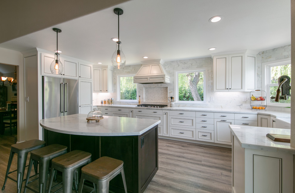 This is an example of a classic u-shaped kitchen in San Francisco with a belfast sink, recessed-panel cabinets, white cabinets, white splashback, stainless steel appliances, dark hardwood flooring, an island and brown floors.