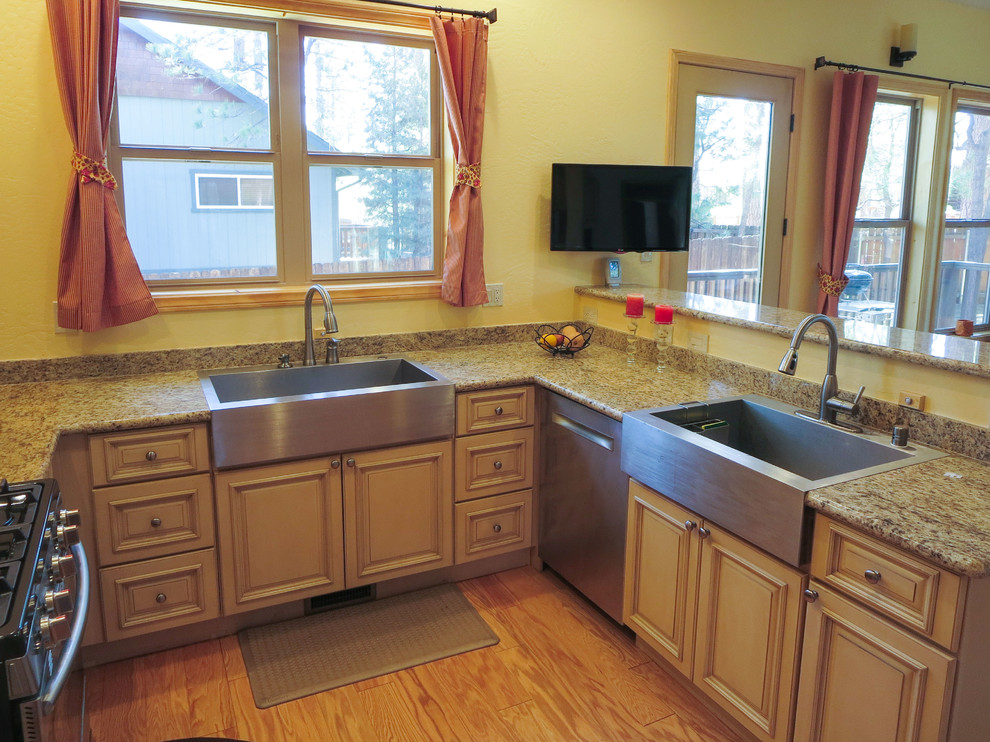 Bild på ett mellanstort medelhavsstil kök, med en rustik diskho, luckor med upphöjd panel, beige skåp, granitbänkskiva, gult stänkskydd, rostfria vitvaror och ljust trägolv