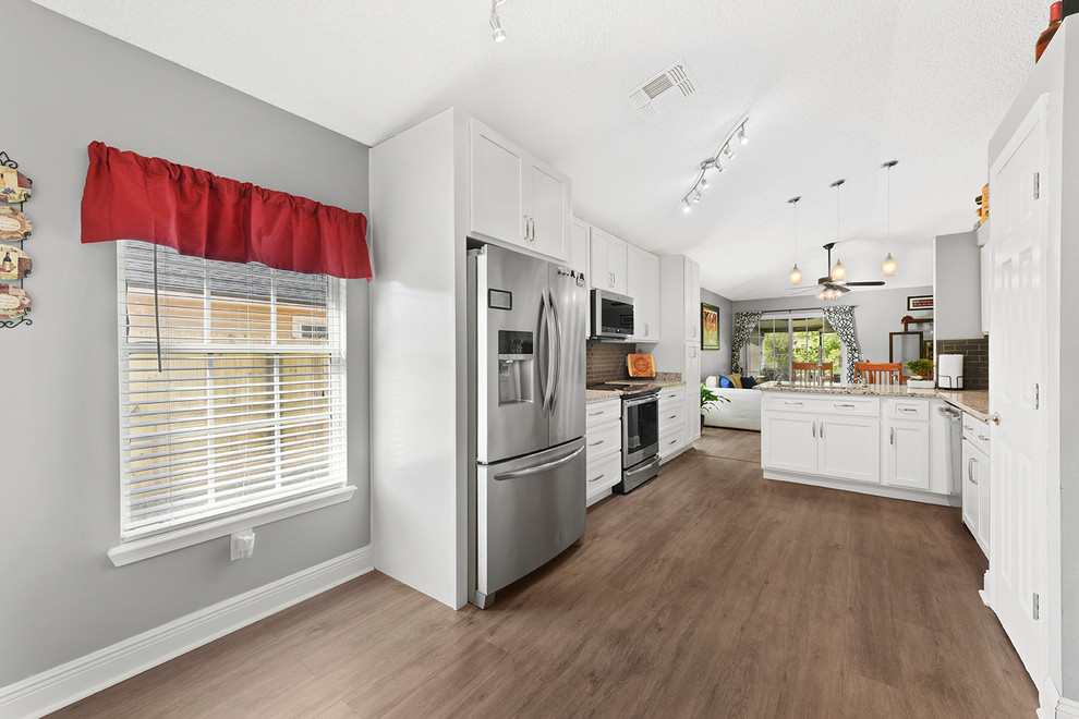 Modern inredning av ett mellanstort grå grått kök, med en enkel diskho, skåp i shakerstil, vita skåp, granitbänkskiva, grått stänkskydd, stänkskydd i glaskakel, rostfria vitvaror, vinylgolv och grått golv