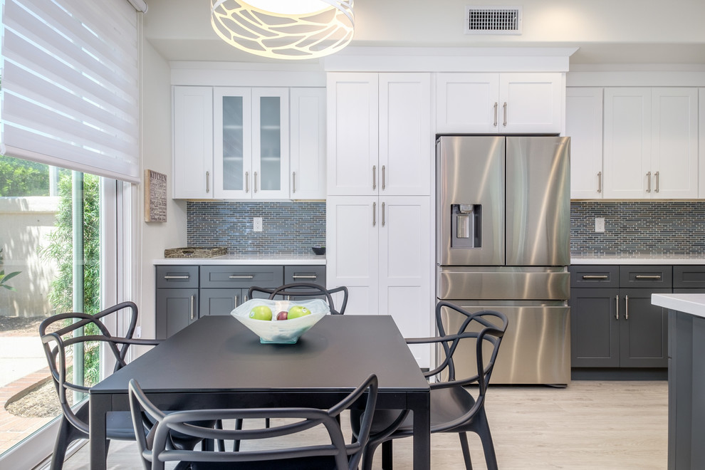 Eat-in kitchen - mid-sized transitional u-shaped light wood floor and beige floor eat-in kitchen idea in Orange County with an undermount sink, shaker cabinets, white cabinets, solid surface countertops, multicolored backsplash, matchstick tile backsplash, stainless steel appliances and a peninsula