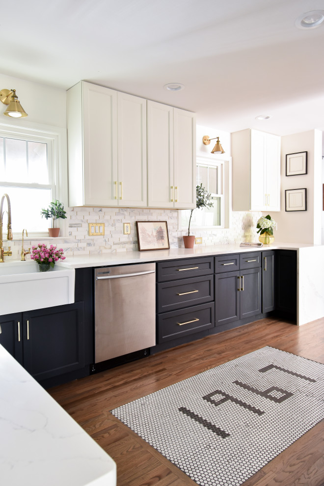 This is an example of a traditional u-shaped kitchen in Other with a belfast sink, recessed-panel cabinets, black cabinets, white splashback, stainless steel appliances, medium hardwood flooring, brown floors and white worktops.
