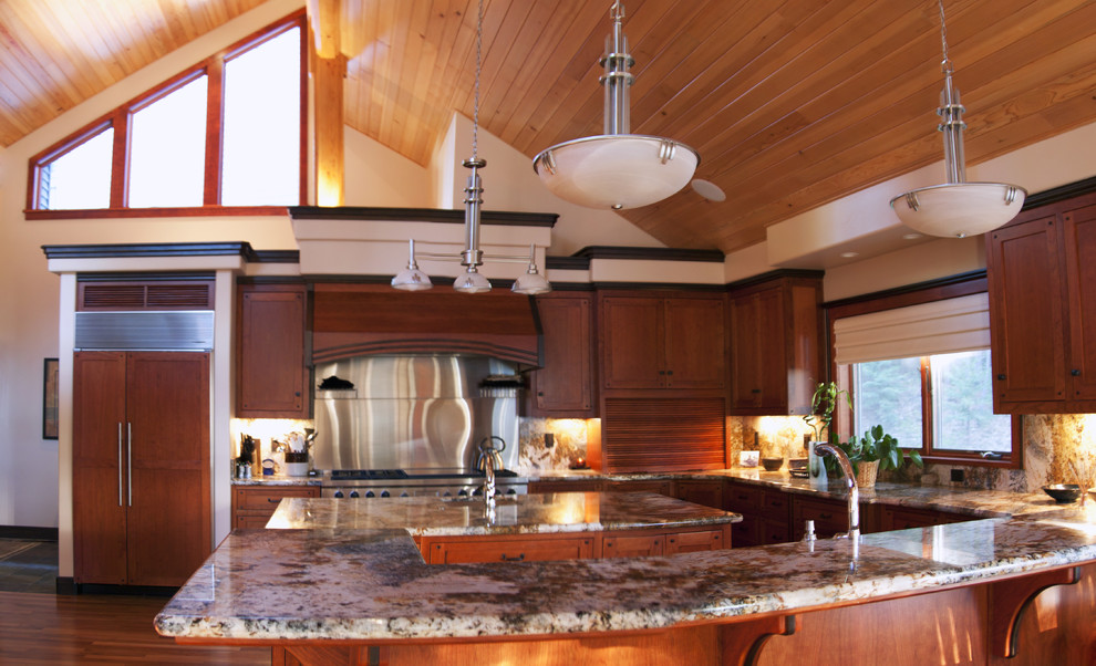 Cette photo montre une très grande cuisine américaine craftsman en U et bois brun avec un évier encastré, un placard à porte shaker, un plan de travail en granite, un électroménager en acier inoxydable, un sol en bois brun et îlot.