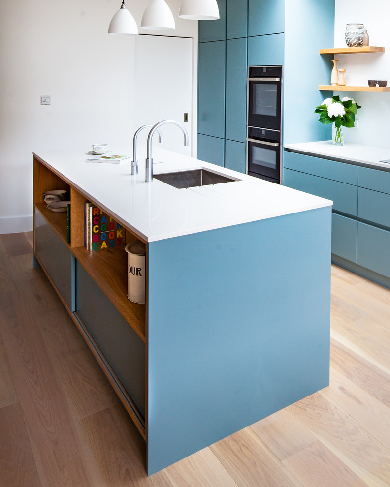 Immagine di una cucina design di medie dimensioni con ante lisce, ante blu, top in quarzite, paraspruzzi bianco, paraspruzzi con lastra di vetro e parquet chiaro