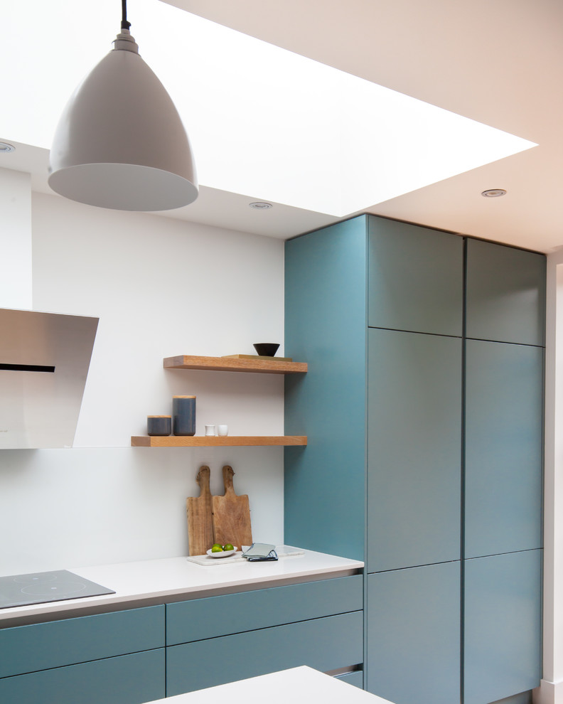 Einzeilige, Mittelgroße Moderne Wohnküche mit flächenbündigen Schrankfronten, blauen Schränken, Quarzit-Arbeitsplatte, Küchenrückwand in Weiß, Glasrückwand, hellem Holzboden und Kücheninsel in London