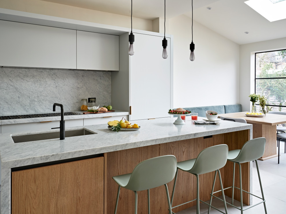 Mid-sized 1950s single-wall gray floor eat-in kitchen photo in London with an undermount sink, flat-panel cabinets, gray cabinets, marble countertops, gray backsplash, marble backsplash, black appliances, an island and gray countertops