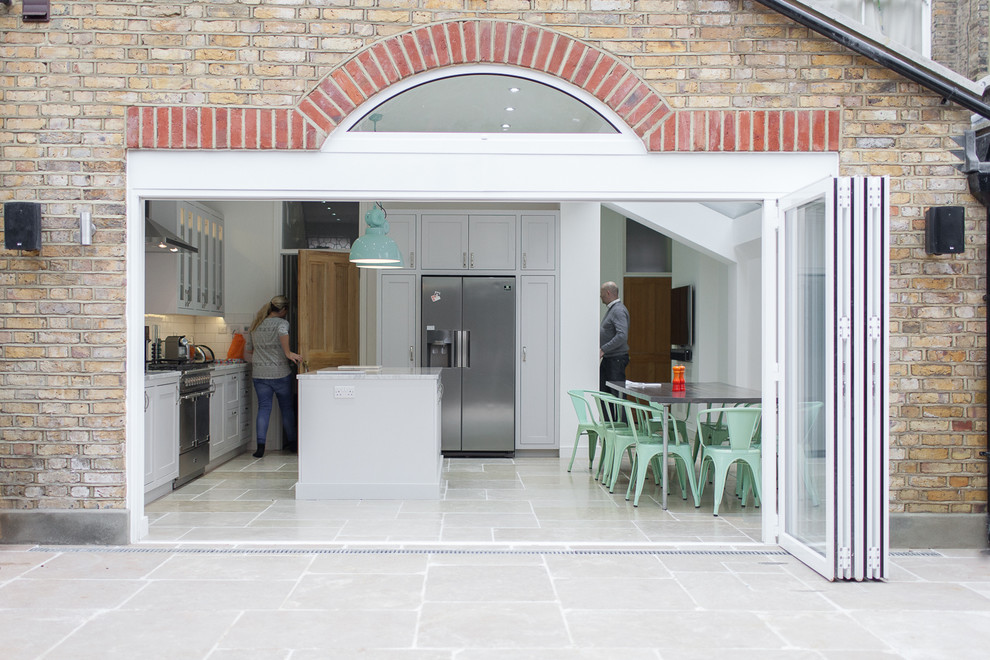 Klassische Wohnküche mit Schrankfronten im Shaker-Stil, weißen Schränken, Küchenrückwand in Weiß, Rückwand aus Metrofliesen, Küchengeräten aus Edelstahl und Kücheninsel in Surrey
