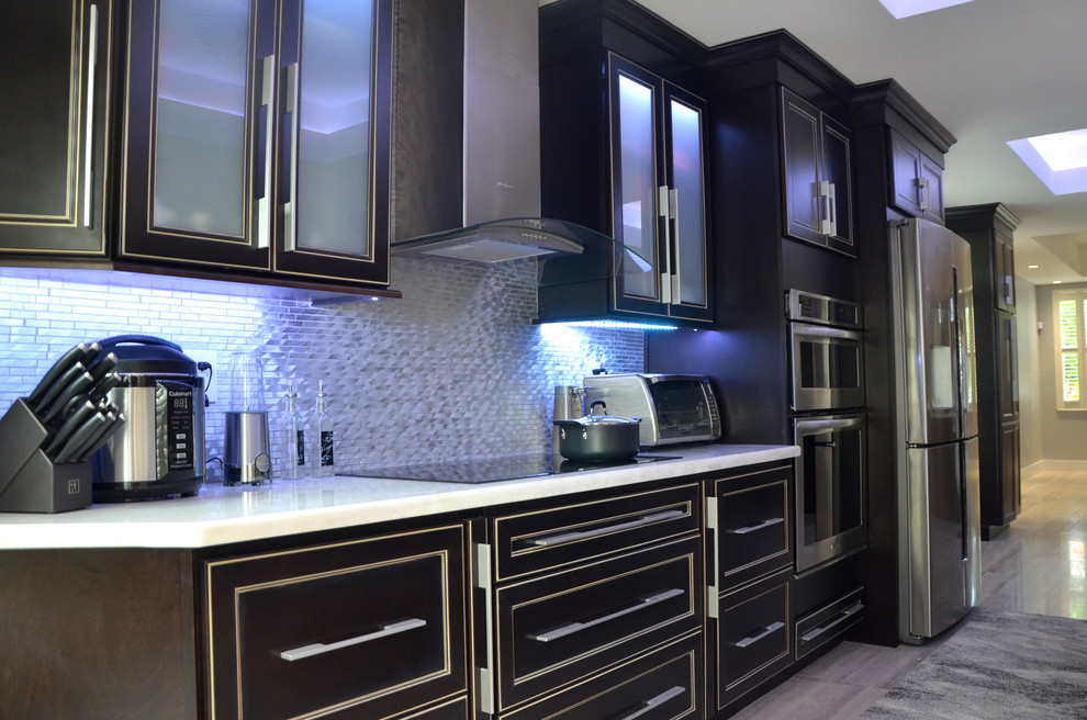 Large modern kitchen/diner in Miami with flat-panel cabinets, dark wood cabinets, marble worktops, metallic splashback, stainless steel appliances, porcelain flooring and a breakfast bar.