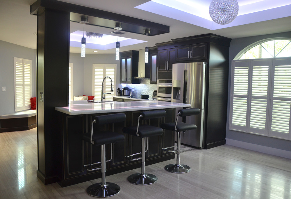 Large modern kitchen/diner in Miami with flat-panel cabinets, dark wood cabinets, marble worktops, metallic splashback, stainless steel appliances, porcelain flooring and a breakfast bar.
