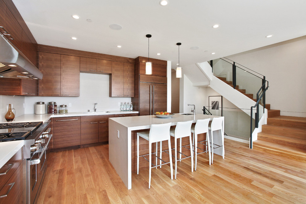 Moderne Küche in L-Form mit flächenbündigen Schrankfronten, dunklen Holzschränken, Elektrogeräten mit Frontblende, braunem Holzboden und Kücheninsel in San Francisco