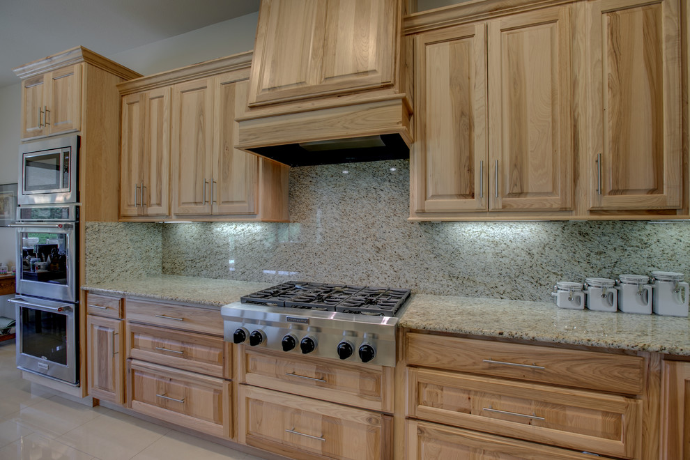 Foto på ett mellanstort rustikt kök, med en dubbel diskho, luckor med upphöjd panel, skåp i ljust trä, granitbänkskiva, beige stänkskydd, stänkskydd i sten, rostfria vitvaror, klinkergolv i porslin, en köksö och beiget golv