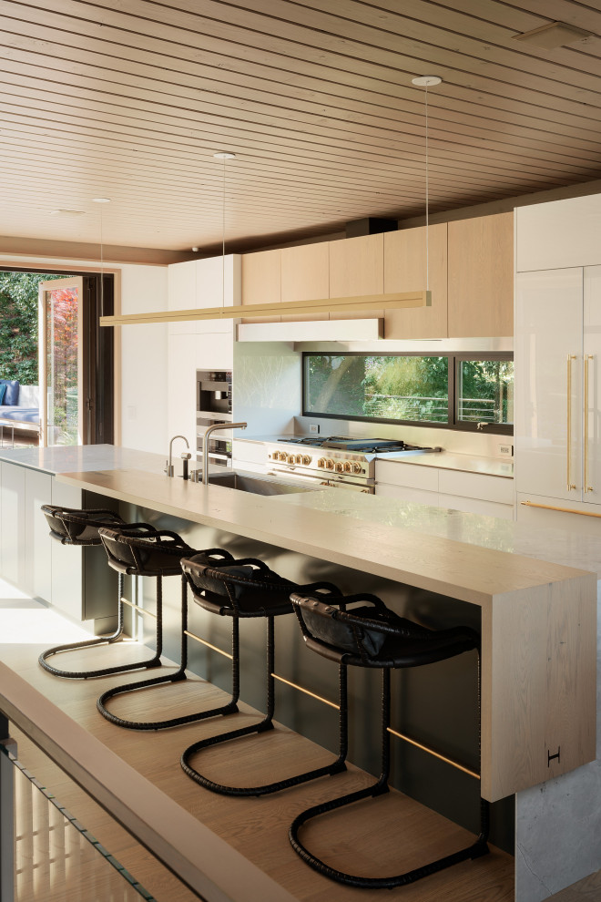 Inspiration for a modern galley medium tone wood floor and brown floor kitchen remodel in San Francisco with an undermount sink, flat-panel cabinets, white cabinets, stainless steel appliances, an island and white countertops