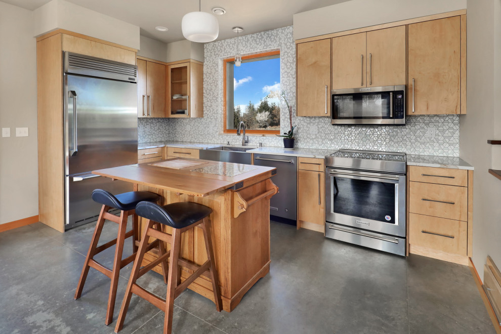 Large mountain style u-shaped concrete floor and gray floor eat-in kitchen photo in Seattle with a farmhouse sink, flat-panel cabinets, light wood cabinets, quartz countertops, gray backsplash, ceramic backsplash, stainless steel appliances, an island and multicolored countertops