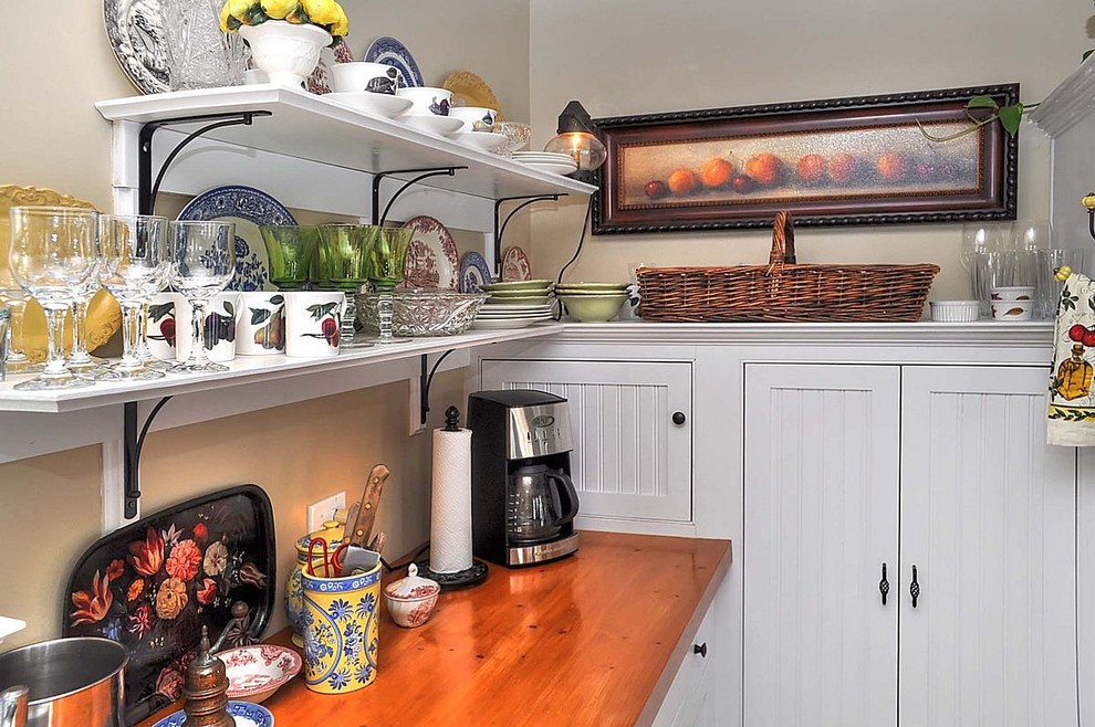 Small beach style single-wall limestone floor eat-in kitchen photo in Milwaukee with a farmhouse sink, beaded inset cabinets, white cabinets, wood countertops, white backsplash, white appliances and an island