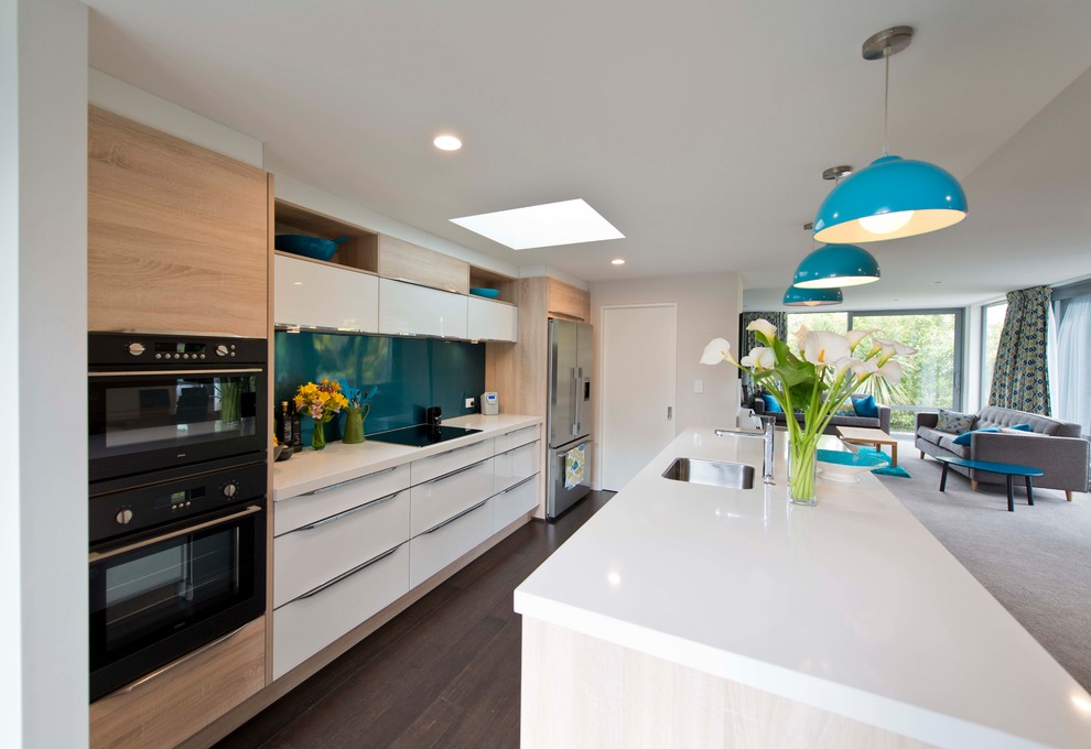 Immagine di una cucina minimal di medie dimensioni con lavello sottopiano, ante bianche, top in quarzo composito, elettrodomestici neri, pavimento in laminato e pavimento marrone