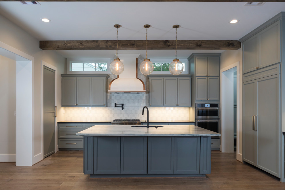 Bild på ett funkis grå grått kök, med en rustik diskho, grå skåp, bänkskiva i kvartsit, vitt stänkskydd, stänkskydd i keramik, rostfria vitvaror, ljust trägolv, en köksö och brunt golv