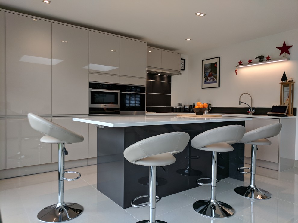 ロンドンにある高級な広いモダンスタイルのおしゃれなキッチン (アンダーカウンターシンク、フラットパネル扉のキャビネット、グレーのキャビネット、珪岩カウンター、黒いキッチンパネル、セメントタイルのキッチンパネル、黒い調理設備、セラミックタイルの床、グレーの床) の写真
